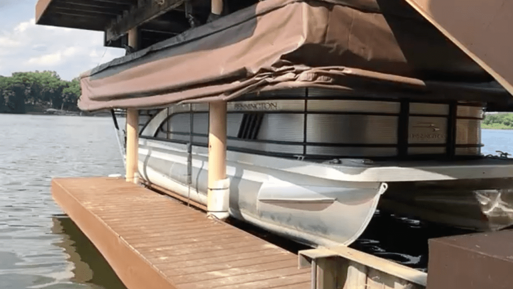 Retracted Touchless Cover® over a pontoon boat stored at the dock