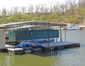 Pontoon Boat Cover. Green lowered. on floating dock.