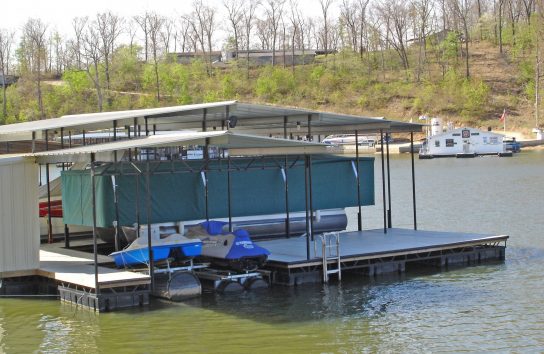 Pontoon Boat Cover. Green lowered. on floating dock.